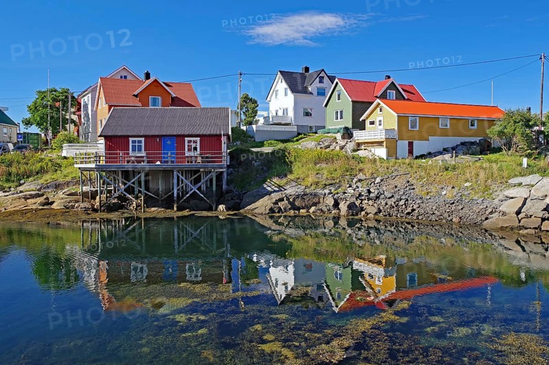 Different coloured hozhouses reflected in crystal clear sea water, Rorbuer, Henningsvaer, Lofoten, Nordland, Norway, Europe