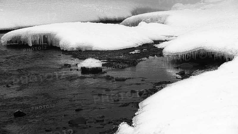 Snow mounds and icicles in the Skoga River below the Skogafoss waterfall, black and white photo, Sudurland, Iceland, Europe