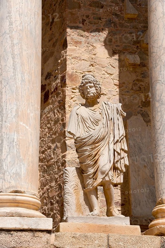 Stone statue in front of ancient columns and stone walls, a detail of Roman architecture and historical sites, Teatro Romano de Mérida, Roman theatre of Merida, Merida, Badajoz, Extremadura, Spain, UNESCO World Heritage Site, Europe