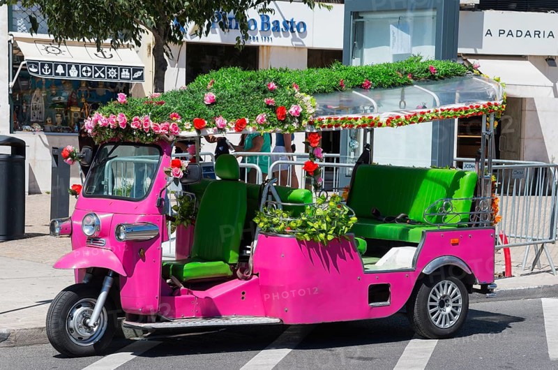 Pink tuk-tuk with green interior and flower garlands in the urban outdoor area, Lisbon, Lisboa, Portugal, Europe