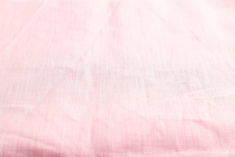 Fragment of smooth pink linen tissue. Side view, natural textile background and texture