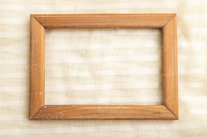 Wooden frame on smooth white linen tissue. Top view, flat lay, natural textile background and texture