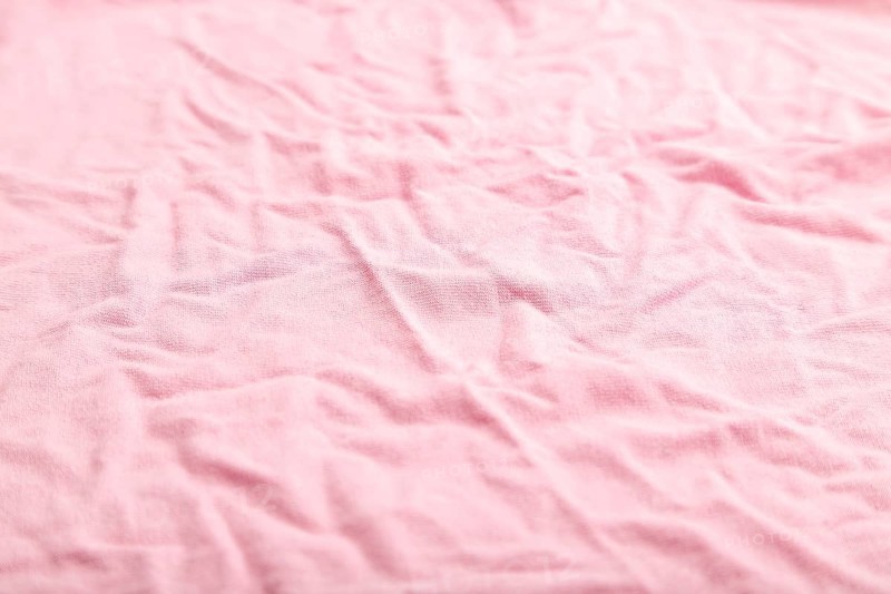 Fragment of pink cotton tissue. Side view, natural textile background and texture