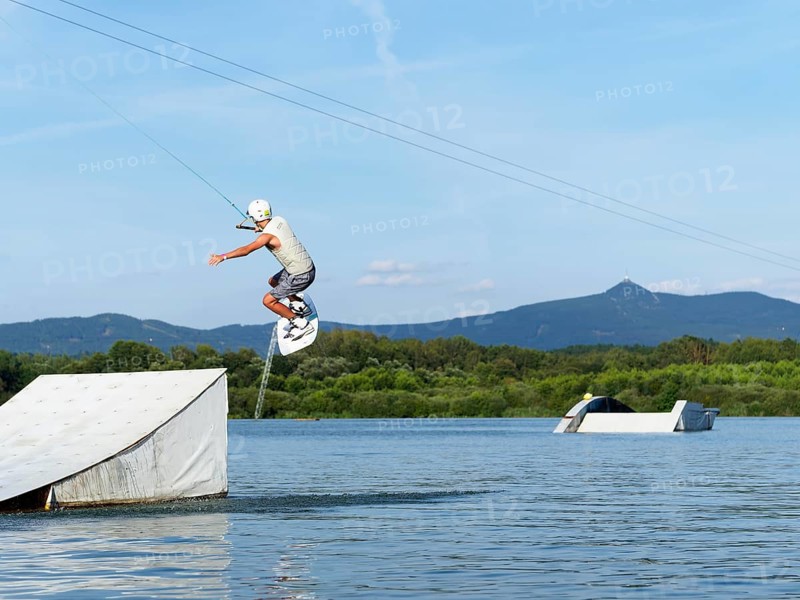 Sporty young man with wakeboard, jump over obstacle, jump, water sports, water skiing and wake park, Stráž pod Ralskem, Czech Republic, Europe