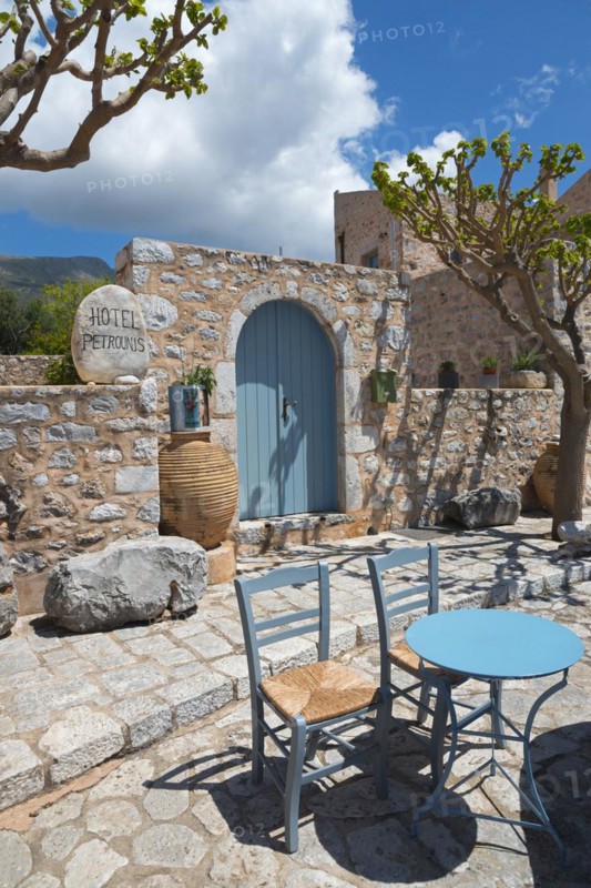 Inviting hotel terrace with stone walls and a blue sky with table and chairs in the shade, Traditional Hotel, Areopoli, Areopolis, Tsimova, Itylo, Anatoliki Mani, Mani, Laconia, Peloponnese, Greece, Europe
