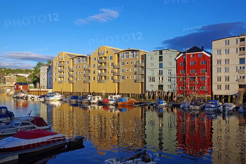 Wooden houses on the waterfront in the evening light with reflections and boats, harbour scene under a cloudy sky, old city centre, Nidarelva, Trondheim, Norway, Europe