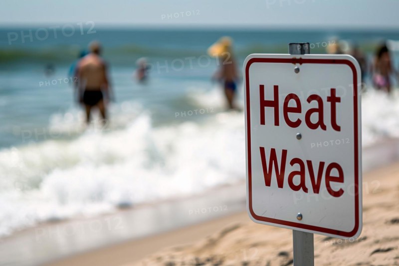 Sign with text 'Heat wave' in front of blurry sunny beach with people. KI generiert, generiert, AI generated