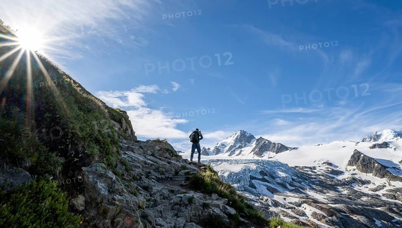 Mountaineer in front of high alpine mountain landscape with sun star, summit of Aiguille de Chardonnet and Glacier du Tour, glacier and mountain peaks, Chamonix, Haute-Savoie, France, Europe