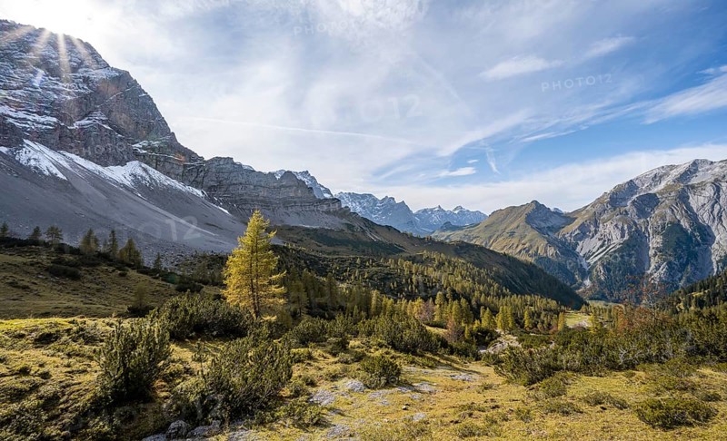Mountain panorama with steep rocky peaks, yellow-coloured larches in autumn, sun star view of the Laliderspitze, Dreizinkenspitze and Spritzkarspitze peaks, hike to the summit of the Hahnkampl, Engtal, Karwendel, Tyrol, Austria, Europe