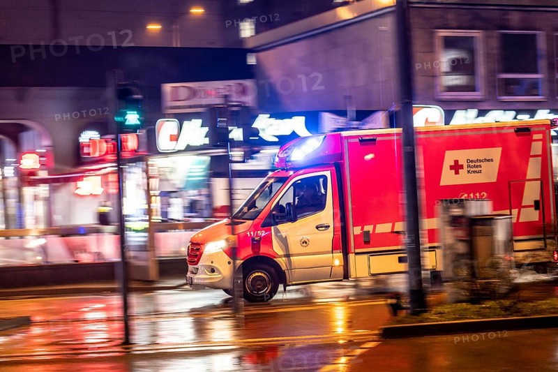 Ambulance on alarm, DRK, Essen fire brigade, rainy weather, city centre, evening, Essen, North Rhine-Westphalia, Germany, Europe