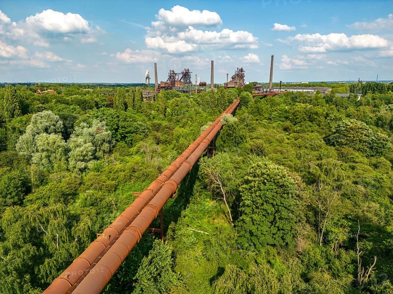 The Duisburg Nord Landscape Park, double blast furnace gas pipeline from the west View across the wilderness, a park area where nature is left to its own devices, to the steelworks, North Rhine-Westphalia, Germany, Europe