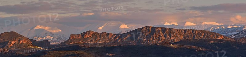 Panoramic shot, Dramatic landscape with snow-capped mountains and rock formations under a cloudy sky at sunset, Lefka Ori, White Mountains, Mountain massif, West, Crete, Greece, Europe