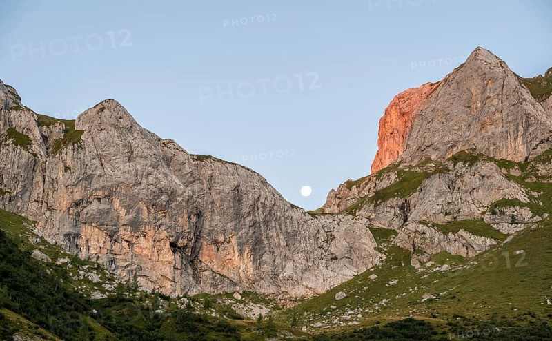 Moon behind rocky peaks at sunrise, alpenglow, Carnic High Trail, Carnic Main Ridge, Carnic Alps, Carinthia, Austria, Europe