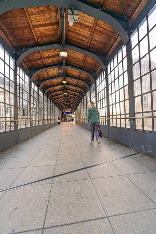 A covered pedestrian bridge in a railway station with glass windows and wooden ceiling, Berlin, Germany, Europe