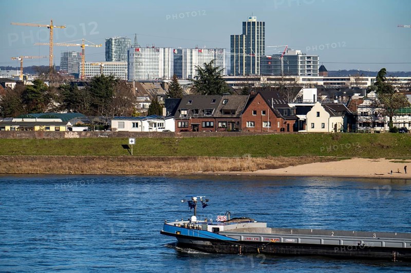 The skyline of Düsseldorf, with the RWI skyscrapers and office buildings on Friedrichstrasse, in front residential buildings on the Rhine in the Hamm district, cargo ship on the Rhine, Düsseldorf, North Rhine-Westphalia, Germany, Europe