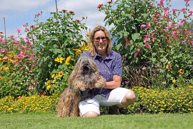 Woman takes Lhasa Apso for a walk in the park