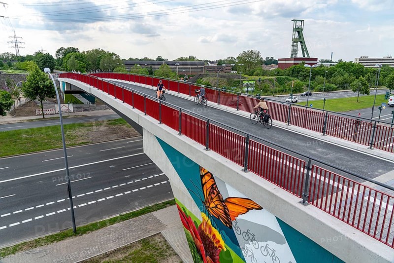 New cycle and footpath bridge, section of the RS1, Ruhr cycle highway, over Berthold-Beitz Boulevard, in the background the pithead of the former Amalie colliery in Essen, North Rhine-Westphalia, Germany, Europe