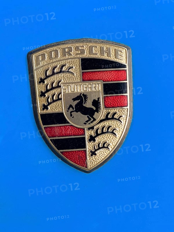 Historic old Porsche crest logo on blue painted bonnet of vintage classic car Porsche 911, international