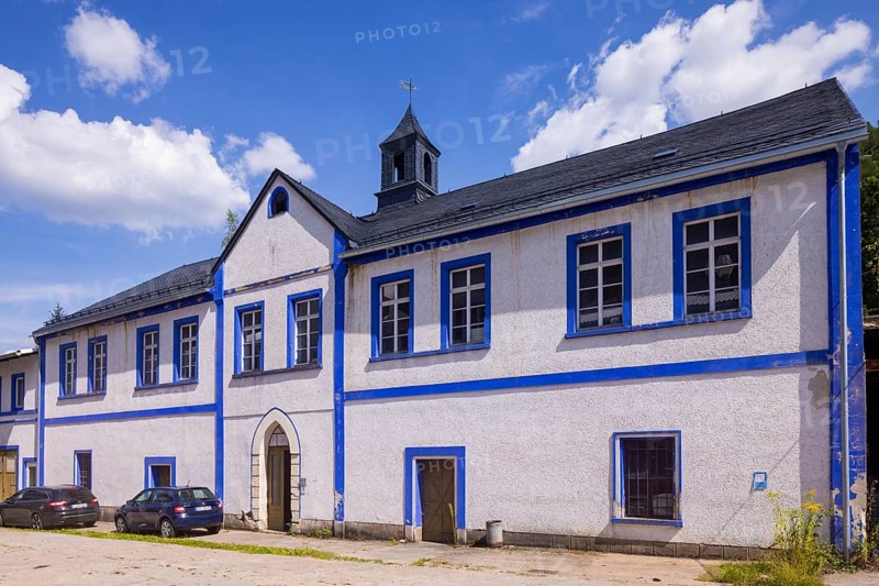 Schindler's blue colour factory is located directly on the Zwickauer Mulde and is part of the Zschorlau district of Albernau in the Saxon Ore Mountains. Since 2019, it has been part of the Schneeberg Mining Landscape and a UNESCO World Heritage Site in the Erzgebirge/Krušnohorí Mining Region. On 27 February 1649, the Schneeberg merchant Erasmus Schindler bought a plot of land to build a blue paint factory on the Zwickauer Mulde near Albernau. On 4 May 1649, he received the privilege to build a blue dye mill from Elector Johann Georg I. As Schindlerswerk GmbH & Co. KG, it is probably the world's oldest paint factory still in production. It is associated with a long tradition of producing blue cobalt pigments and the commercial manufacture of colour pigments. In more recent times, production has been expanded to include various paints. Laundry blue is also produced. Manor house and building of the packing plant, bathing plant, dispatch department, Schindlerswerk, Zschorlau OT Albernau, S...