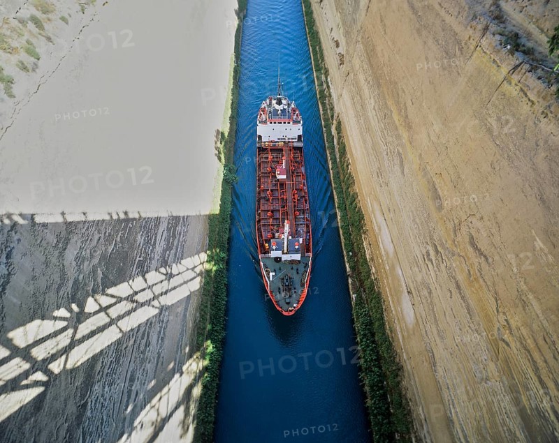 Aerial view of a red ship travelling through a narrow channel under a bridge, Corinth Canal, Corinth, Peloponnese, Greece, Europe