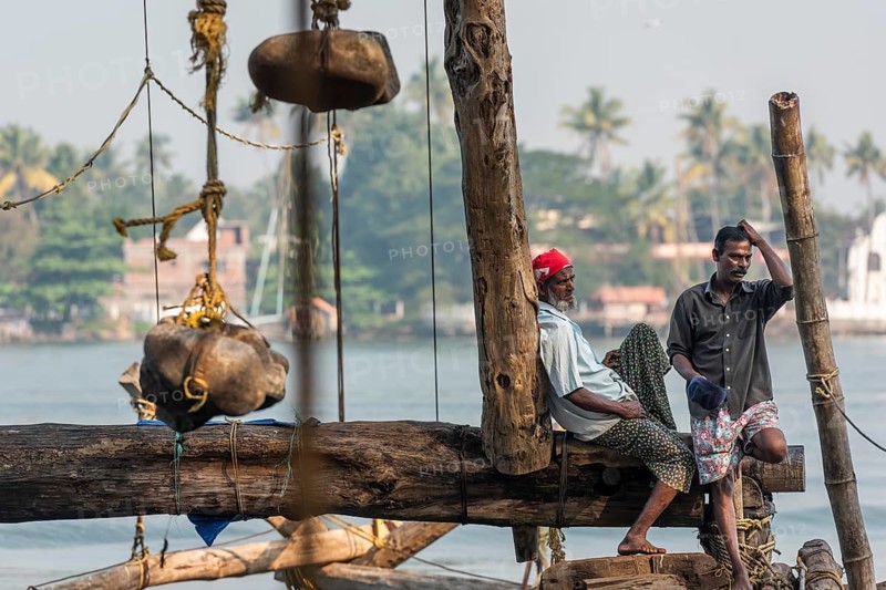 Fishermen resting, heavy stones attached to ropes, Chinese fishing nets, sunset, Arabian Sea coast, Fort Cochin, Kochi, Kerala, South India, India, Asia