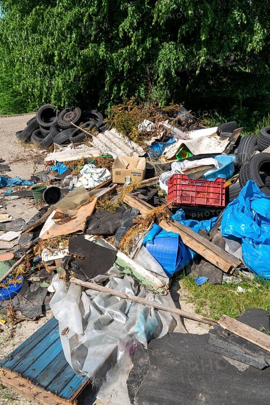 Illegally disposed waste, car tyres, building rubble, household waste, clothing, on a path next to a main road in Bochum, North Rhine-Westphalia, Germany, Europe