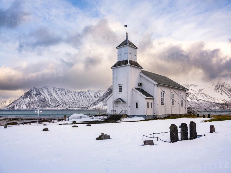 Gimsøy church with cemetery, snow-covered mountains in the background, winter, Gimsøya, Lofoten, Norway, Europe