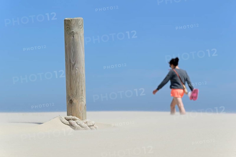 Boundary post on the beach, rope blown over by sand, person crossing the sand drifts, blue sky, North Sea, Juist, East Frisian Islands, Lower Saxony, Germany, Europe