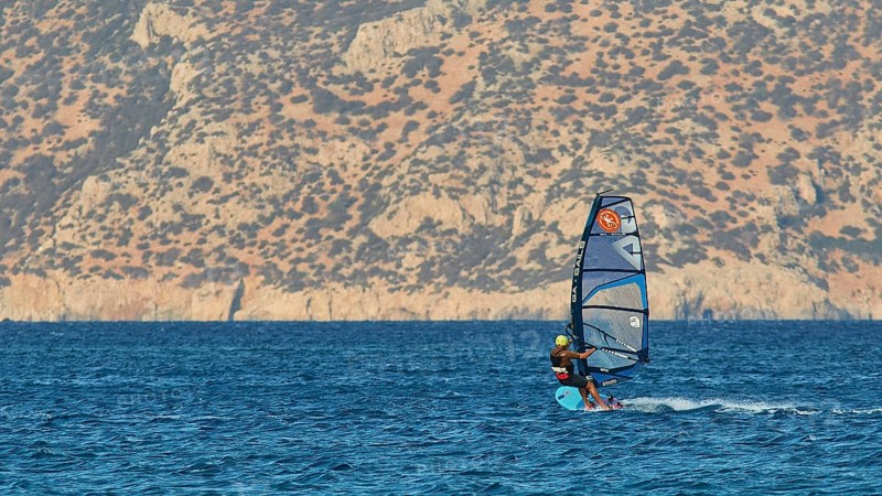 Windsurfer with view of rocky coast, clear blue water, windsurfer, Meltemi windsurfing area, Devils Bay, Paralia Vatha, Vatha Beach, south-east coast, Karpathos, Dodecanese, Greek Islands, Greece, Europe