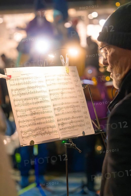 A musician on stage concentrates on his sheet music in the spotlight, Christmas market, Nagold, Black Forest, Germany, Europe