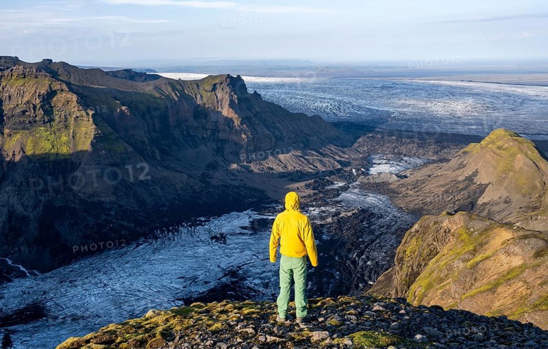 Young man, tourist in front of impressive landscape with glacier in the evening light, glacier tongues Huldujökull and Kötlujökull, Myrdalsjökull glacier, Pakgil, Iceland, Europe