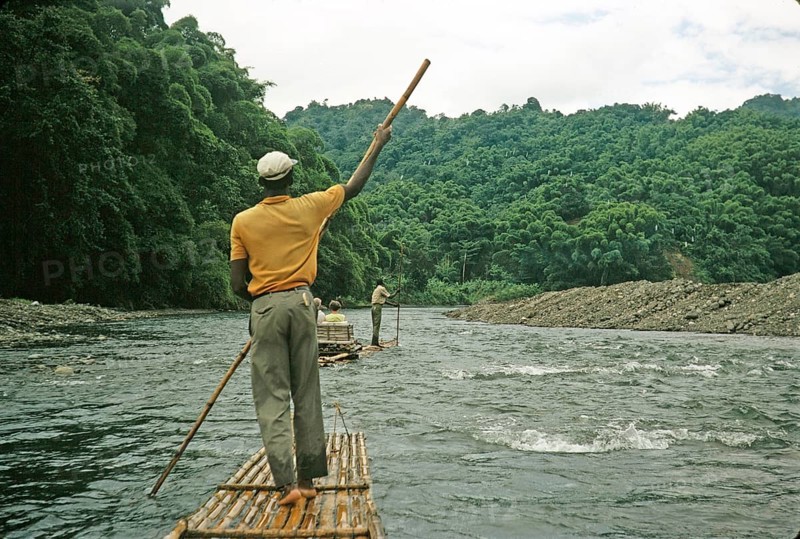 Rafting on the Rio Grande, Port Antonio, Jamaica, Caribbean 1970 Man pushes raft down river through tropical rainforest, Central America