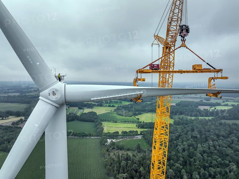 Dorsten, North Rhine-Westphalia, Germany, construction of a wind turbine. A large mobile crane lifts a rotor blade to the nacelle on the tower. Here, the blade is mounted directly on the motor hub. Große Heide wind farm, Europe