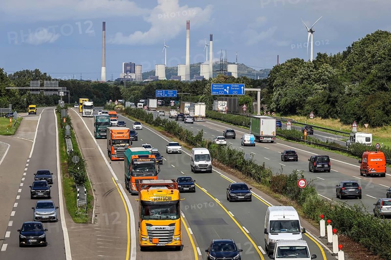 Bottrop, Ruhr area, North Rhine-Westphalia, Germany, rush hour traffic, many lorries driving on the A2 motorway, behind the Uniper coal-fired power plant Gelsenkirchen Scholven, on the right a wind turbine, industry and traffic in the Ruhr area, Europe