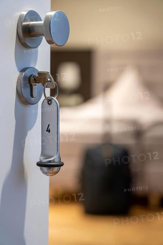 Symbolic image of a hotel, key inserted in the door of a hotel room, analogue lock