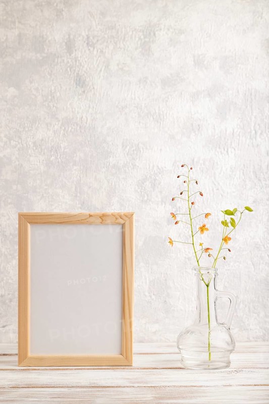 Wooden frame with orange barrenwort flowers in glass on gray concrete background. side view, copy space, still life, mockup, template, spring, summer minimalism concept