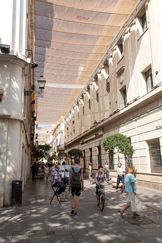 Fabric spread over buildings to provide shade in busy shopping street called Velazquez in central Seville, Spain, Europe