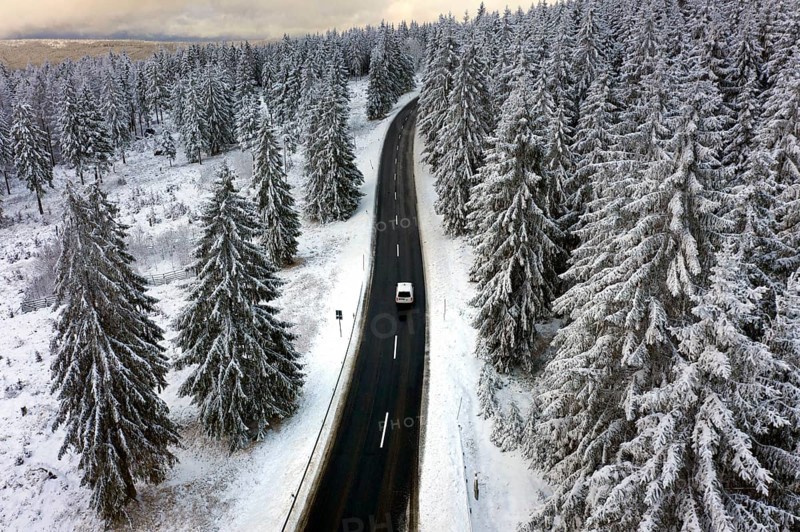 Aerial view, road leads through a snow-covered forest area near Sankt Andreasberg, 14 December 2019