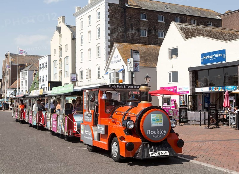 Rockley Rocket land train passing old historic buildings on quayside at Poole harbour, Poole, Dorset, England, UK
