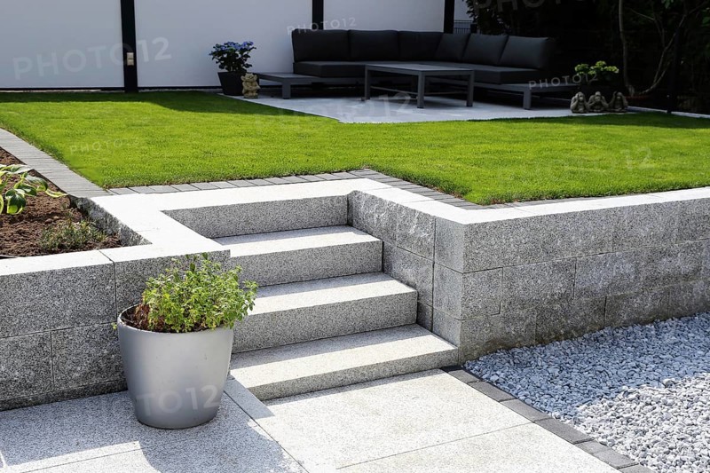 Well-kept ornamental garden with granite wall and block steps