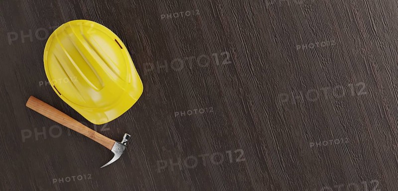 Overhead of yellow hard hat and hammer on a wood surface with room for text