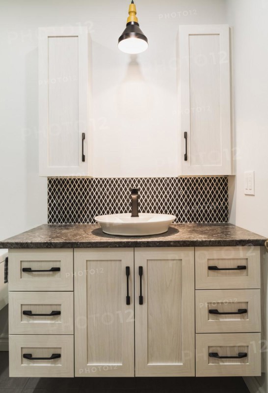 Antique finish wooden cabinet with black nuanced laminated countertop and ceramic backsplash in bathroom inside contemporary home, Quebec, Canada, North America