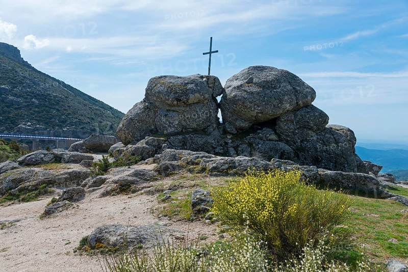A cross stands between large rocks in a natural landscape under a sunny sky, at the Puerto del Pico, Sierra de Gredos, Ávila, Avila, Castilla y León, Leon, Spain, Europe
