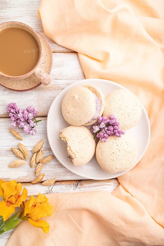 Meringues cakes with cup of coffee on a white wooden background and orange linen textile. Top view, flat lay, close up