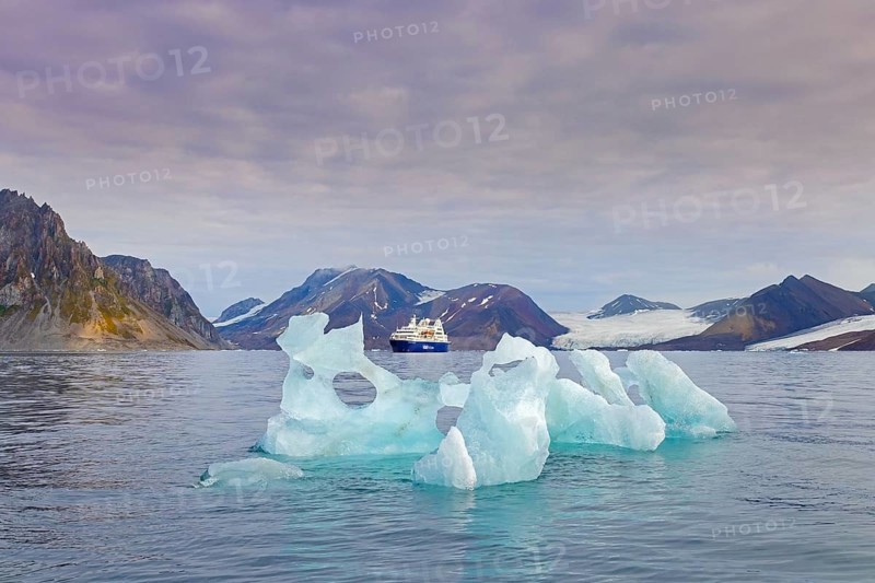 Melting iceberg and cruise ship Ocean Diamond of Iceland ProCruises in the Hornsund fjord in summer, Svalbard, Spitsbergen, Norway, Europe