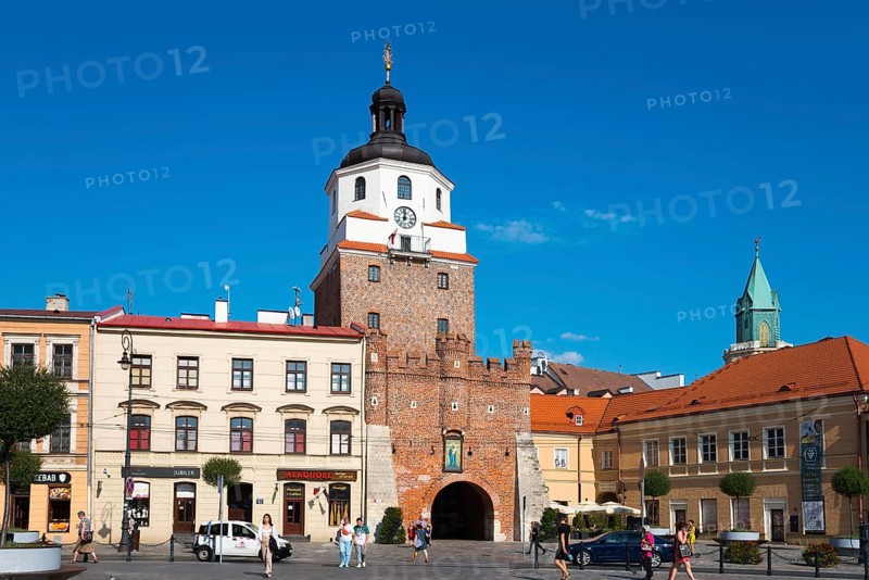 Historic city gate with brick tower and turrets in front of a lively square with passers-by, Krakow Gate, Brama Krakowska, Lokietka Square, Lublin, Poland, Europe