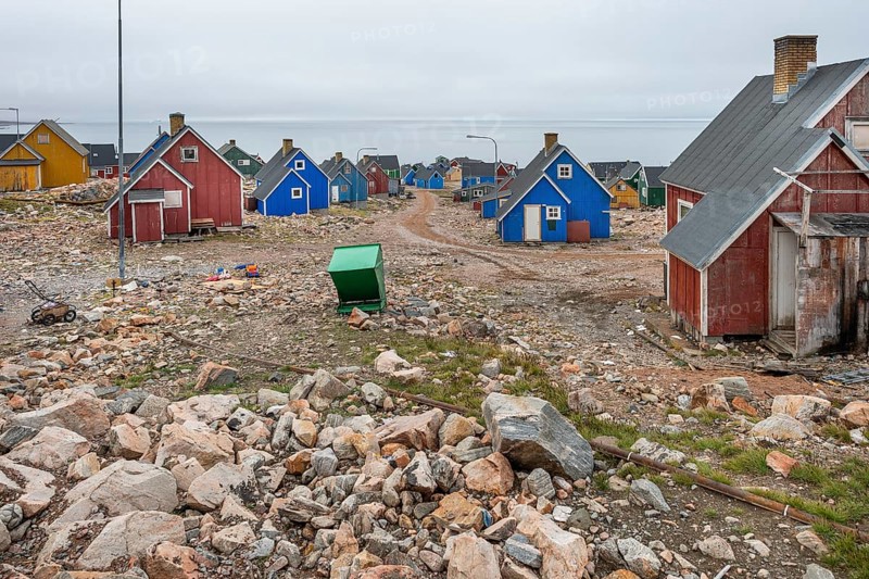 Colourful houses and gravel road under an overcast sky on a fjord, remote Arctic Inuit settlement Ittoqqortoormiit, Scoresbysund or Scoresby Sund or Greenlandic Kangertittivaq, East Greenland, Greenland, North America