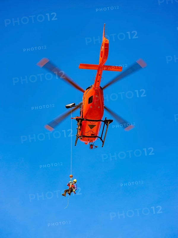 Mountain rescuer of the Bavarian Mountain Rescue Service being winched by the on-board mechanic of the rescue helicopter Christoph 14 with the cable winch, Bad Reichenhall, Berchtesgadener Land, Upper Bavaria, Bavaria, Germany, Europe