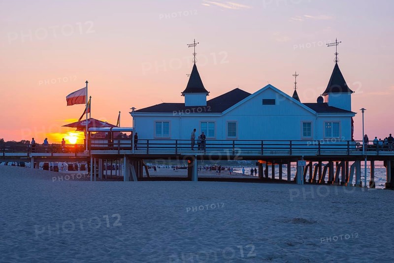 People strolling on a pier with buildings in the sunset, clear, blue, cloudless sky, pier Ahlbeck in the last sunlight, view from the eastern beach to the west, seaside resort Ahlbeck, island Usedom, Mecklenburg-Western Pomerania, Germany, Europe