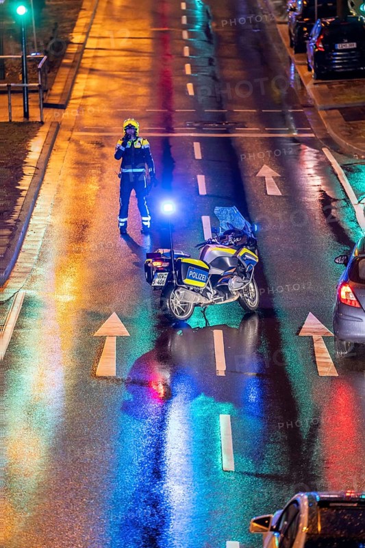 Policeman with motorbike, in rainy weather, blocking a road, police motorbike with blue light